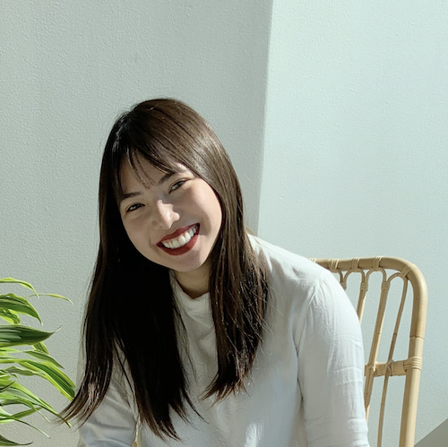 A photo of an Asian woman, Marion, with long dark hair wearing a whitetop  and smiling at you, the viewer